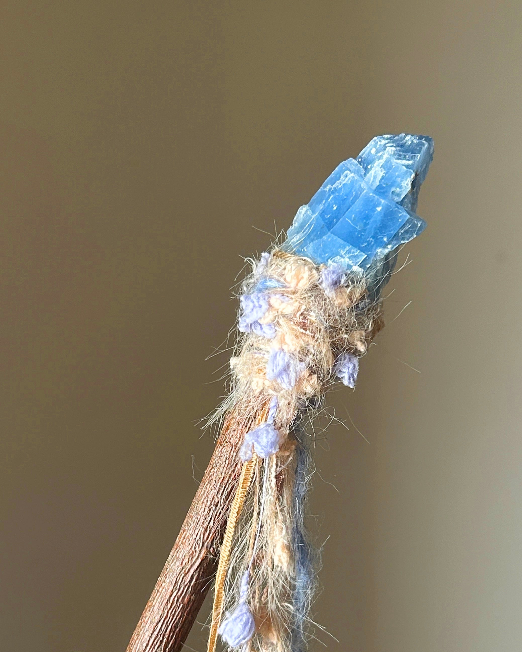 Back view of blue calcite wand with beige and lavender yarn on applewood handle