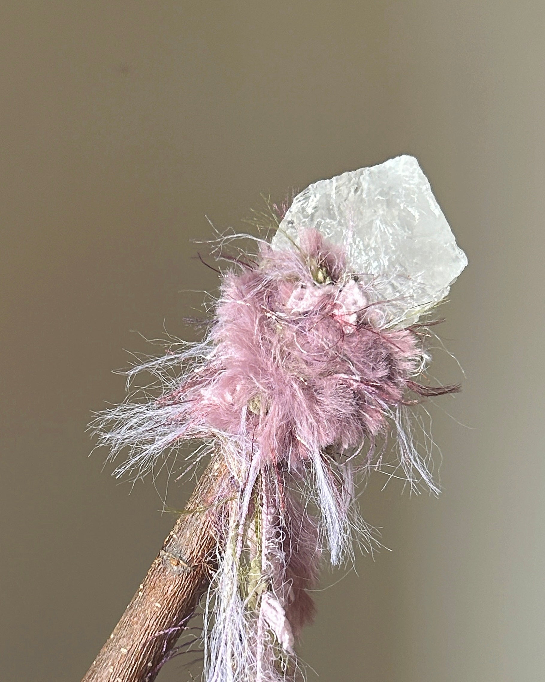 Back view of clear quartz ritual wand with soft fluffy threads and grounding wood