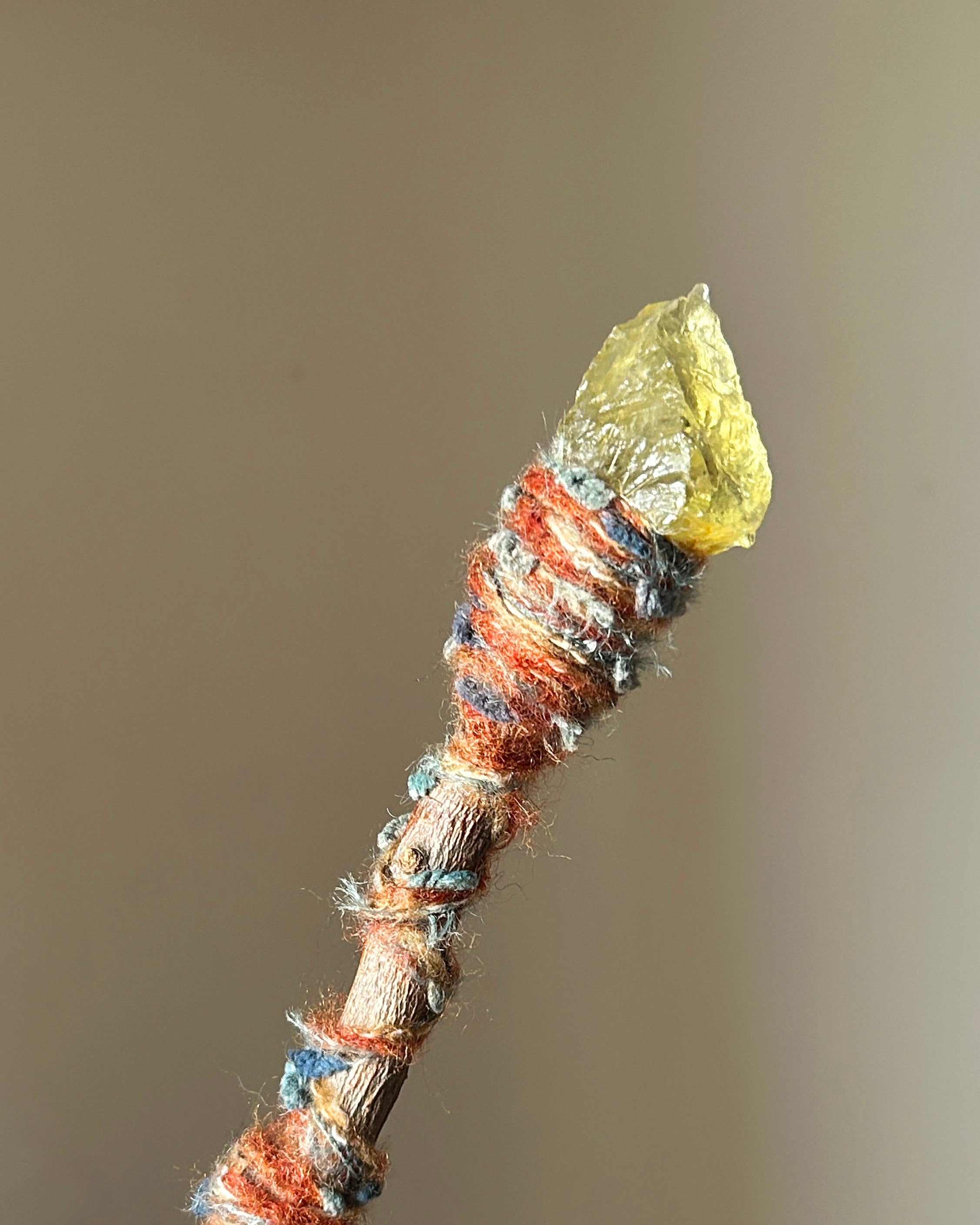 Close-up of raw citrine point and flame-inspired threadwork on ritual wand