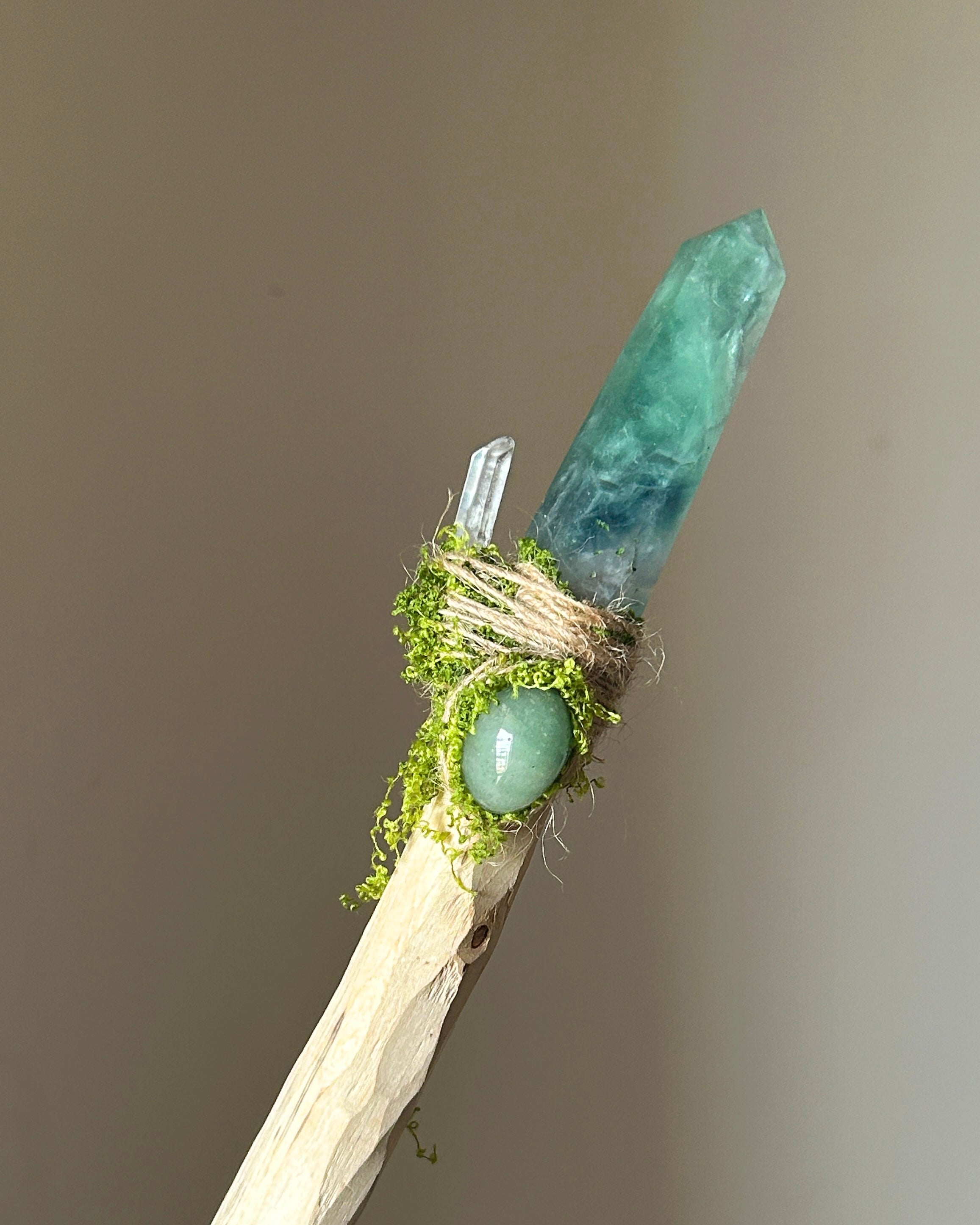 Front view of birch wand with blue-green fluorite, aventurine cabochon, and moss wrap
