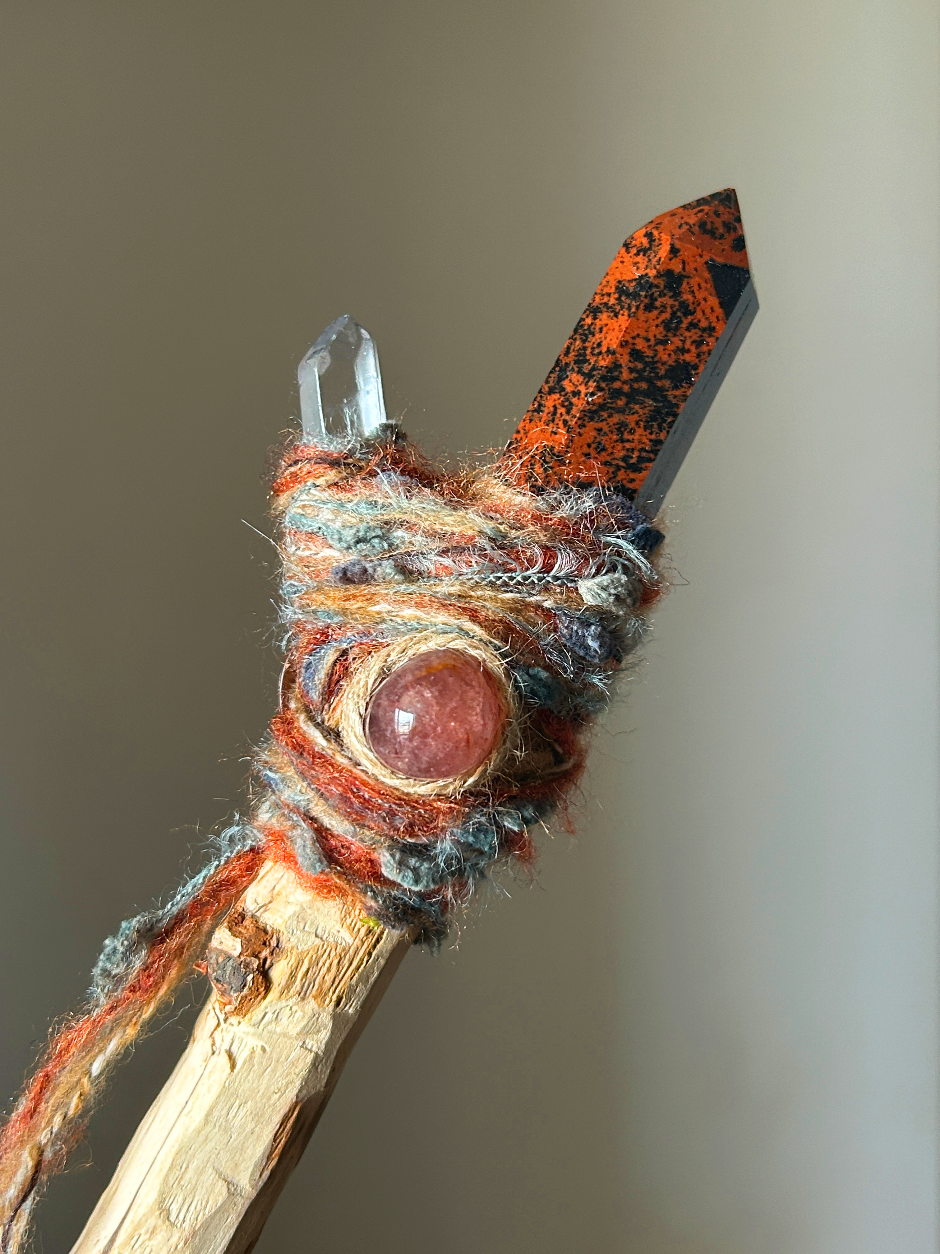 Close-up of obsidian point and pink quartz cabochon on rustic fiber wrap