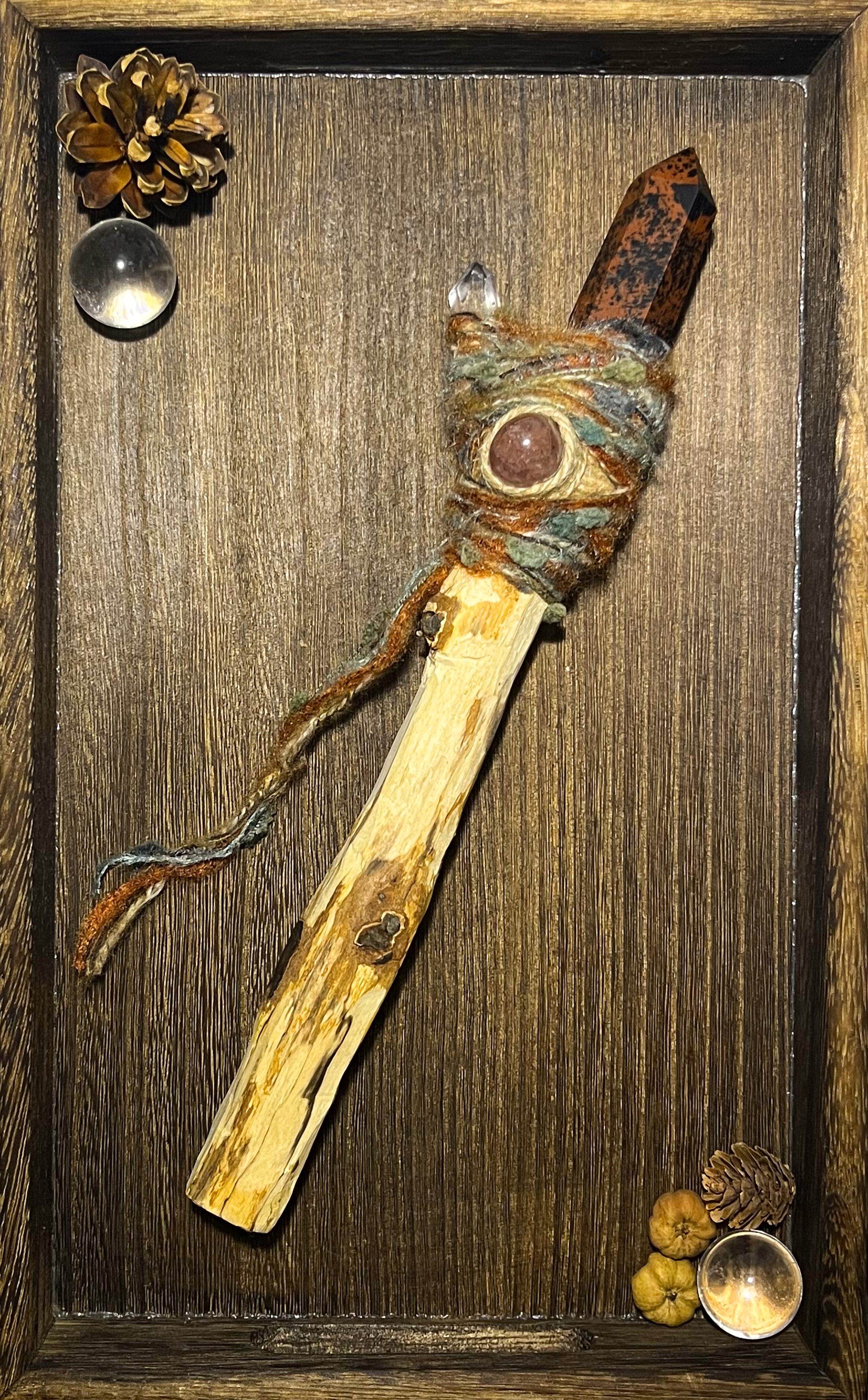 Flatlay photo of protective wand with ember-like yarn and quartz accent