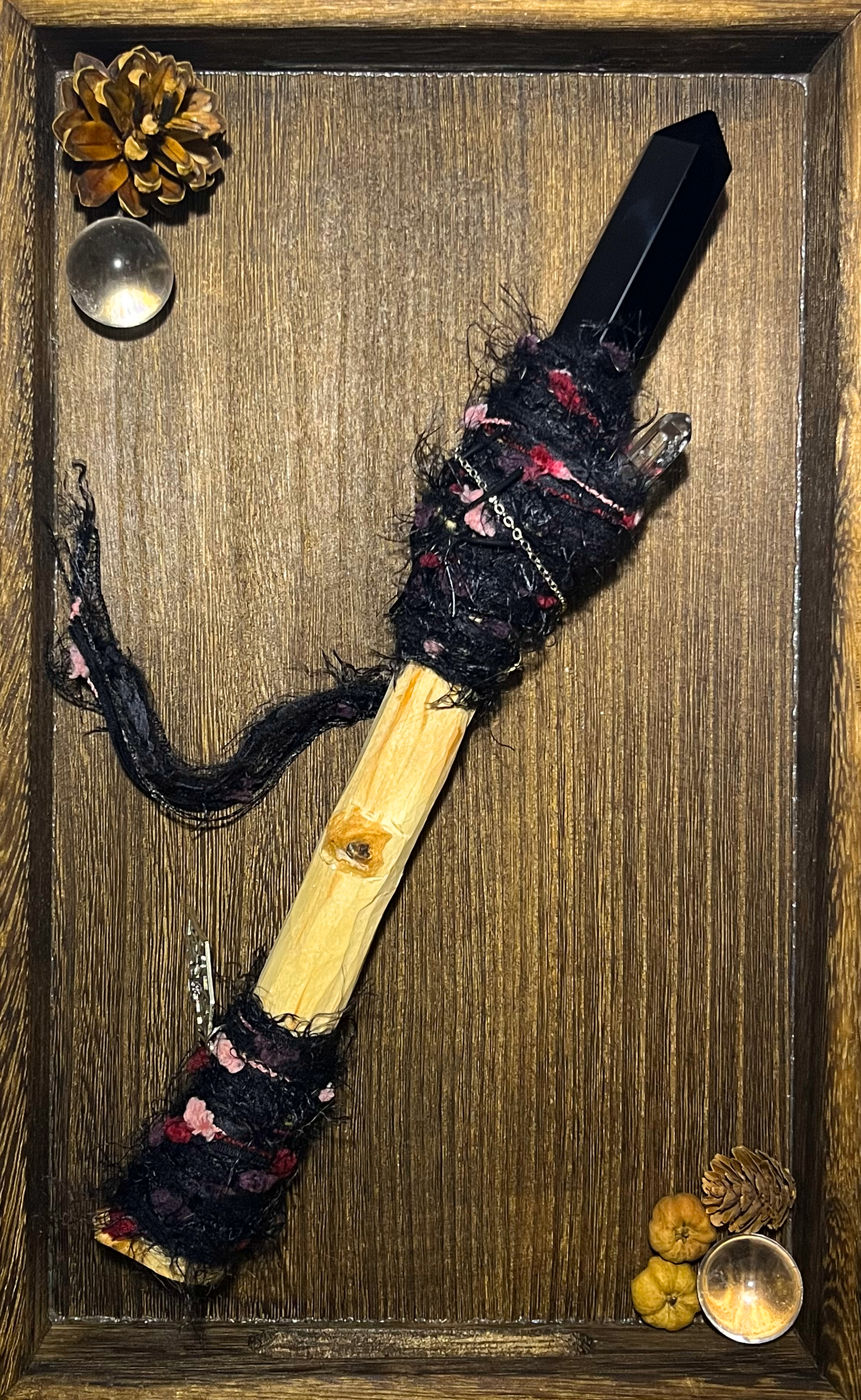 Flatlay showing full wand with obsidian point and crimson threadwork