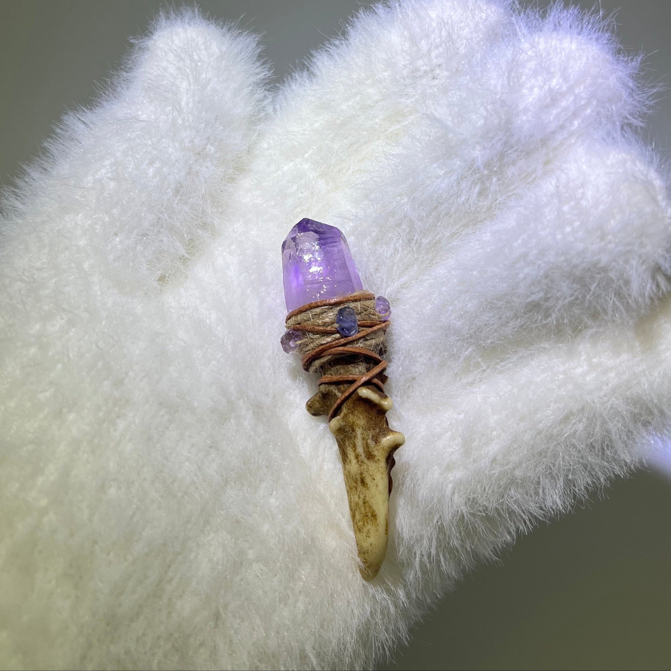 Close-up of high-clarity Cruzite antler wand with enhydro inclusion and amethyst accents, held in a white gloved hand