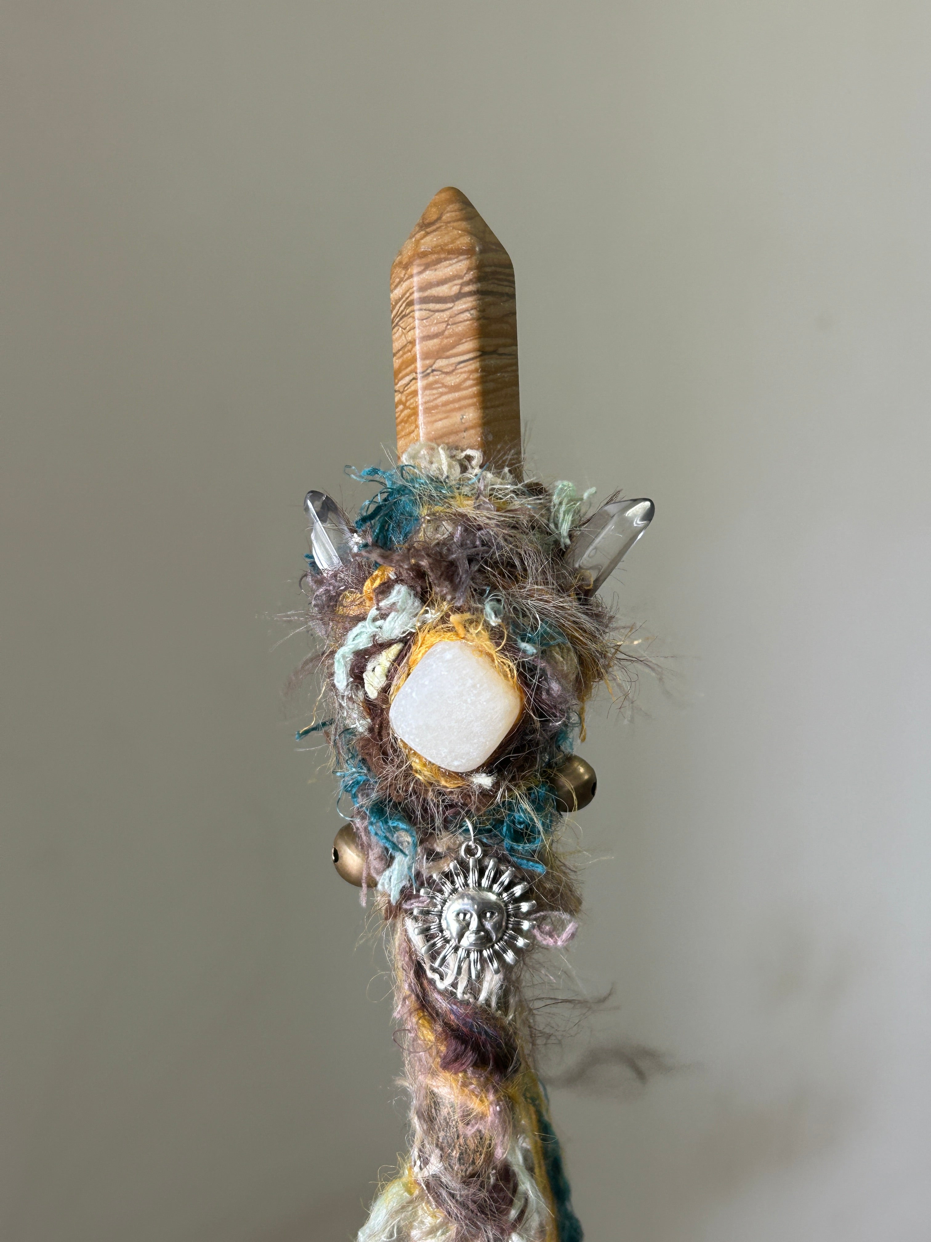 Close-up of picture jasper and calcite cluster on earth-toned wand