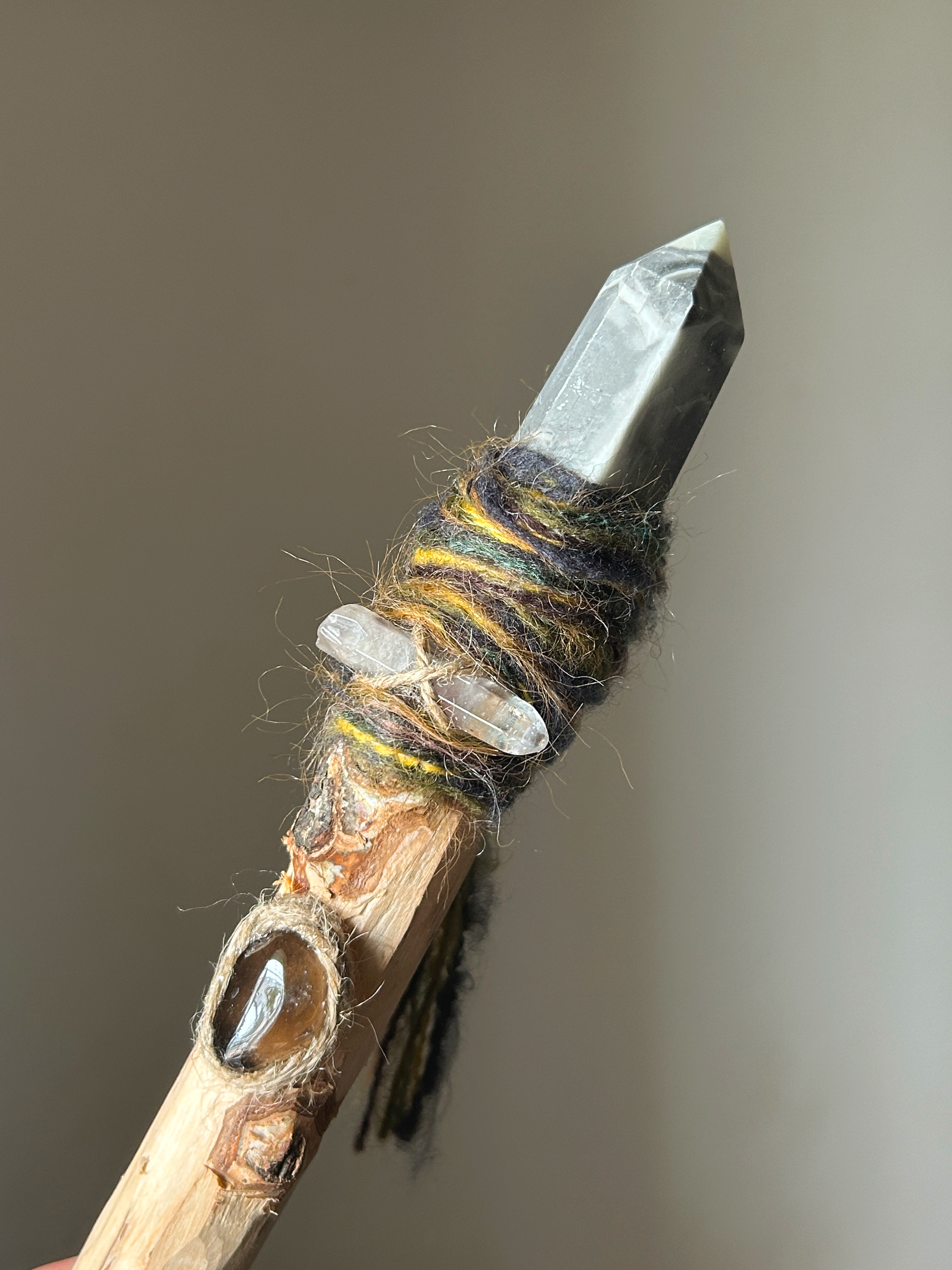 Close-up of grey agate crystal tip and embedded gemstone in tree knot with wool yarn