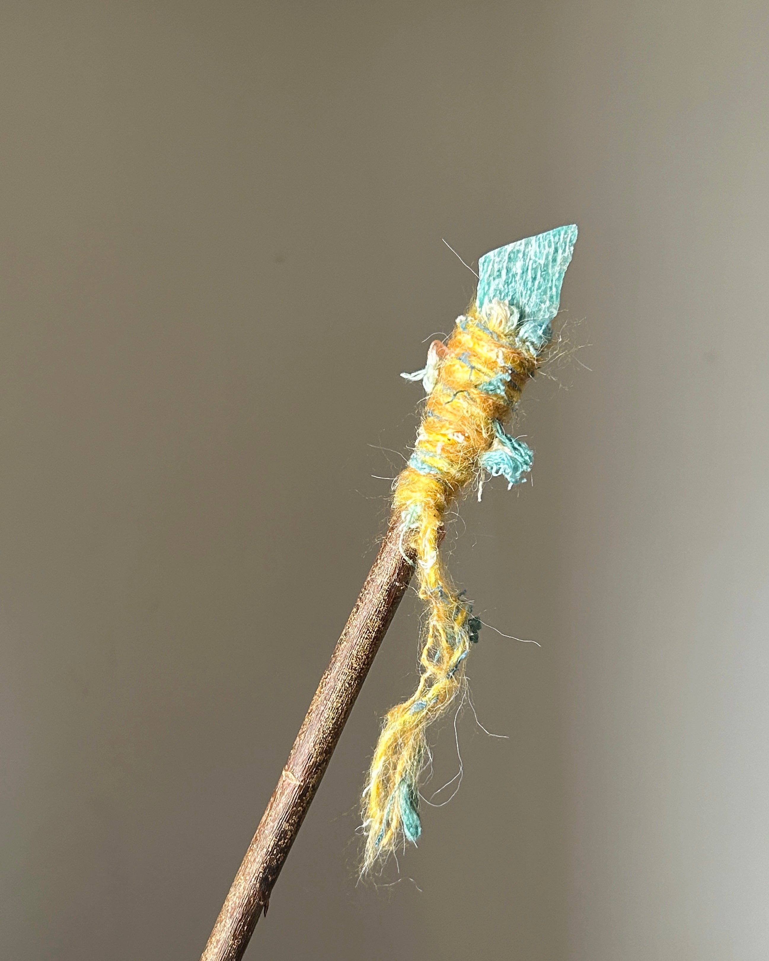 Back view of vibrant amazonite wand with colorful fibers and natural wood grain