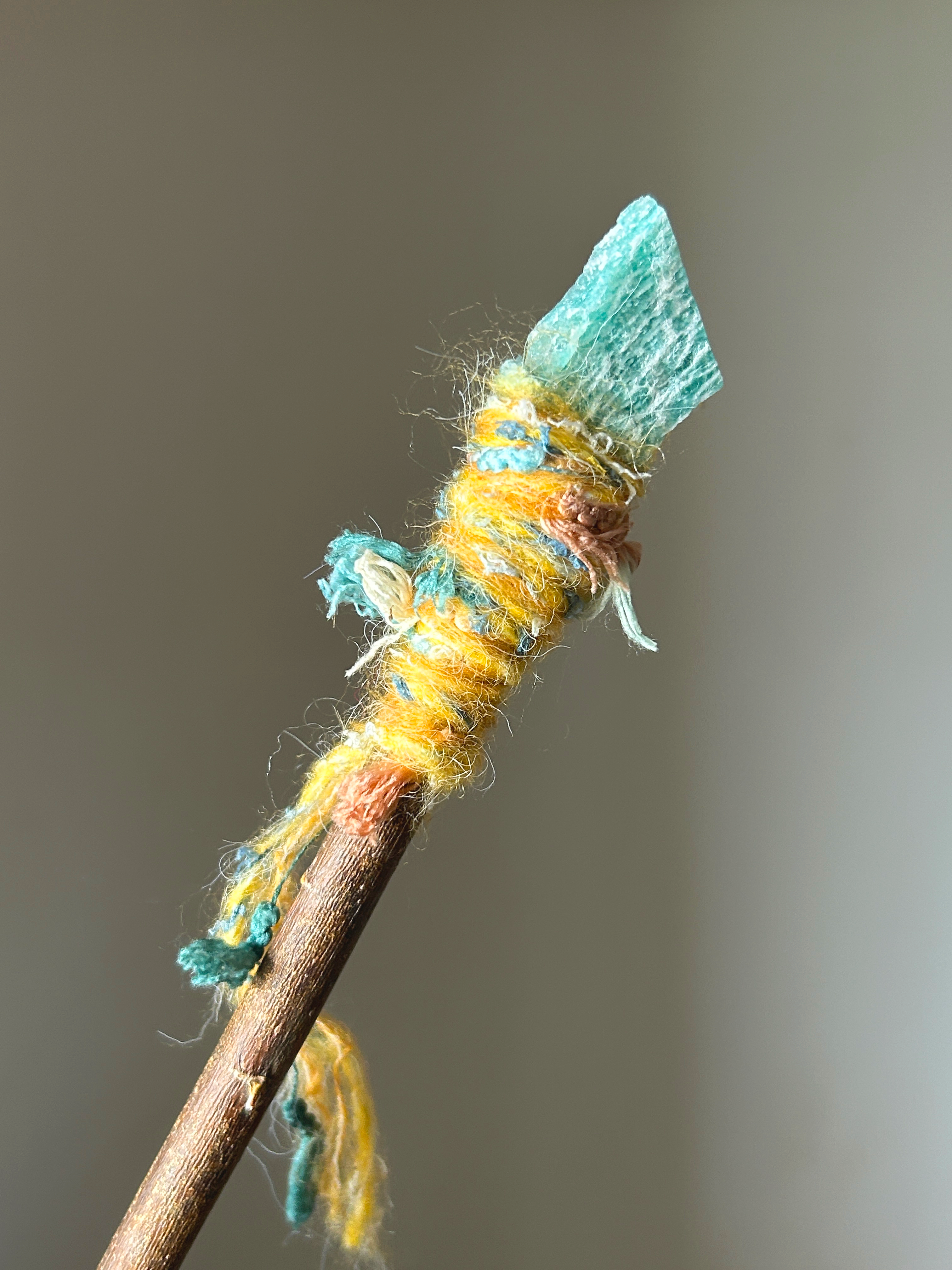Close-up of raw amazonite crystal with playful thread details on willow wand