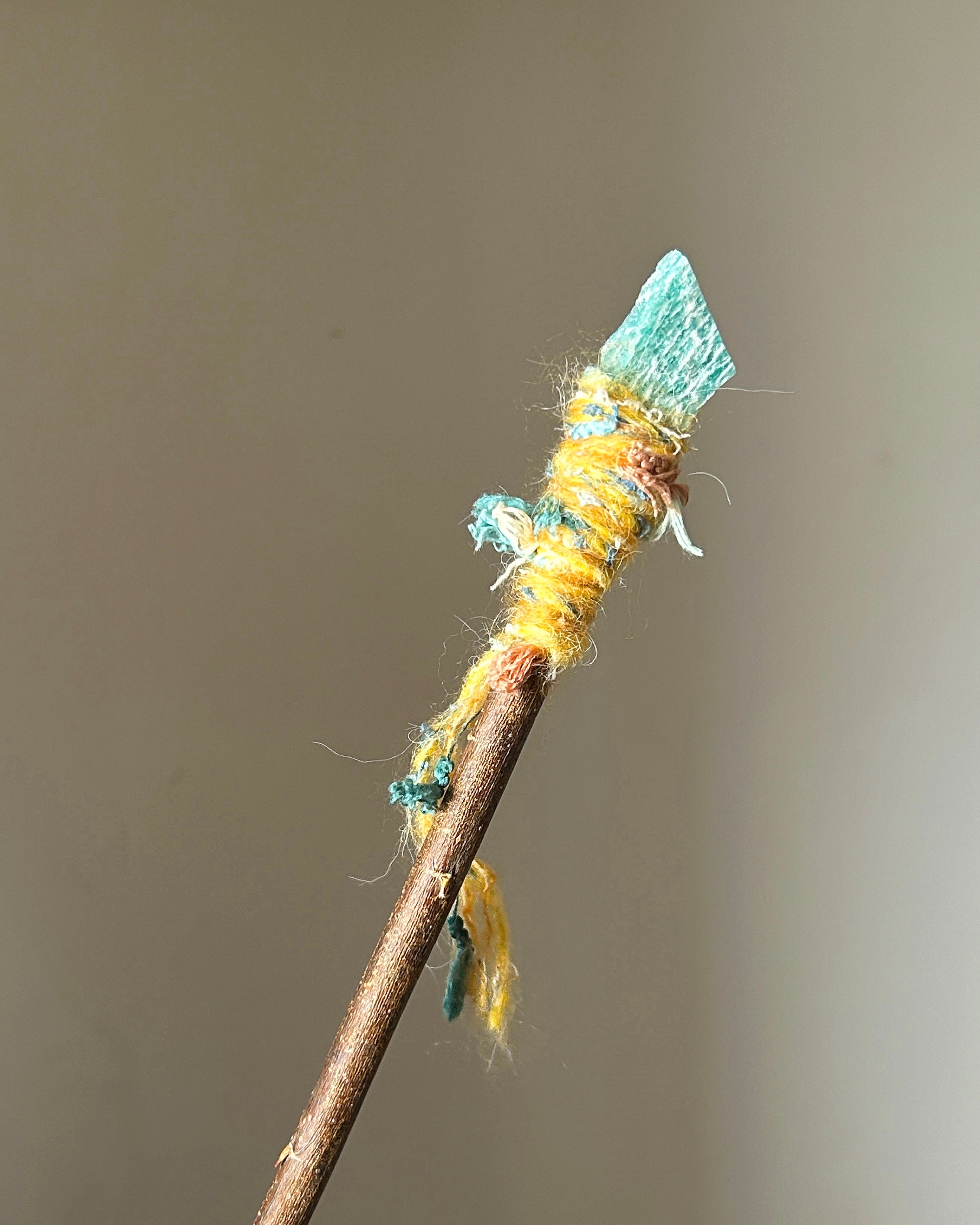 Front view of willow wand with raw amazonite and yellow-turquoise thread wrapping