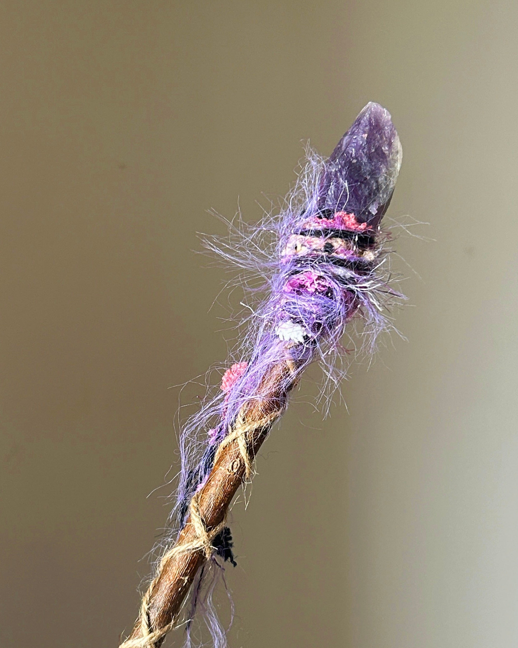 Front view of willow wand with raw amethyst point and purple-pink fiber wrapping