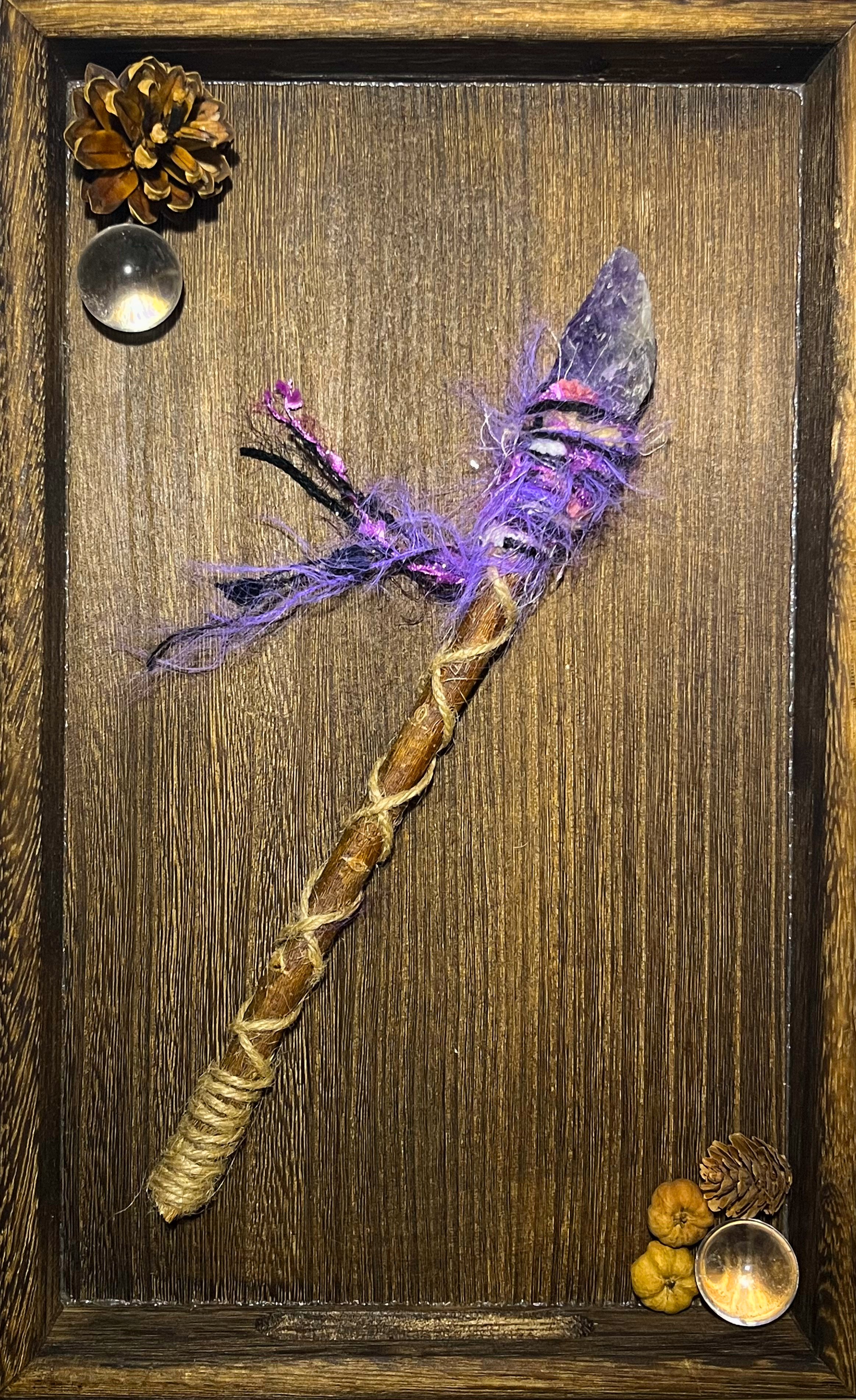 Flat lay of mystical dreamwork wand with raw amethyst and vibrant fiber wrapping