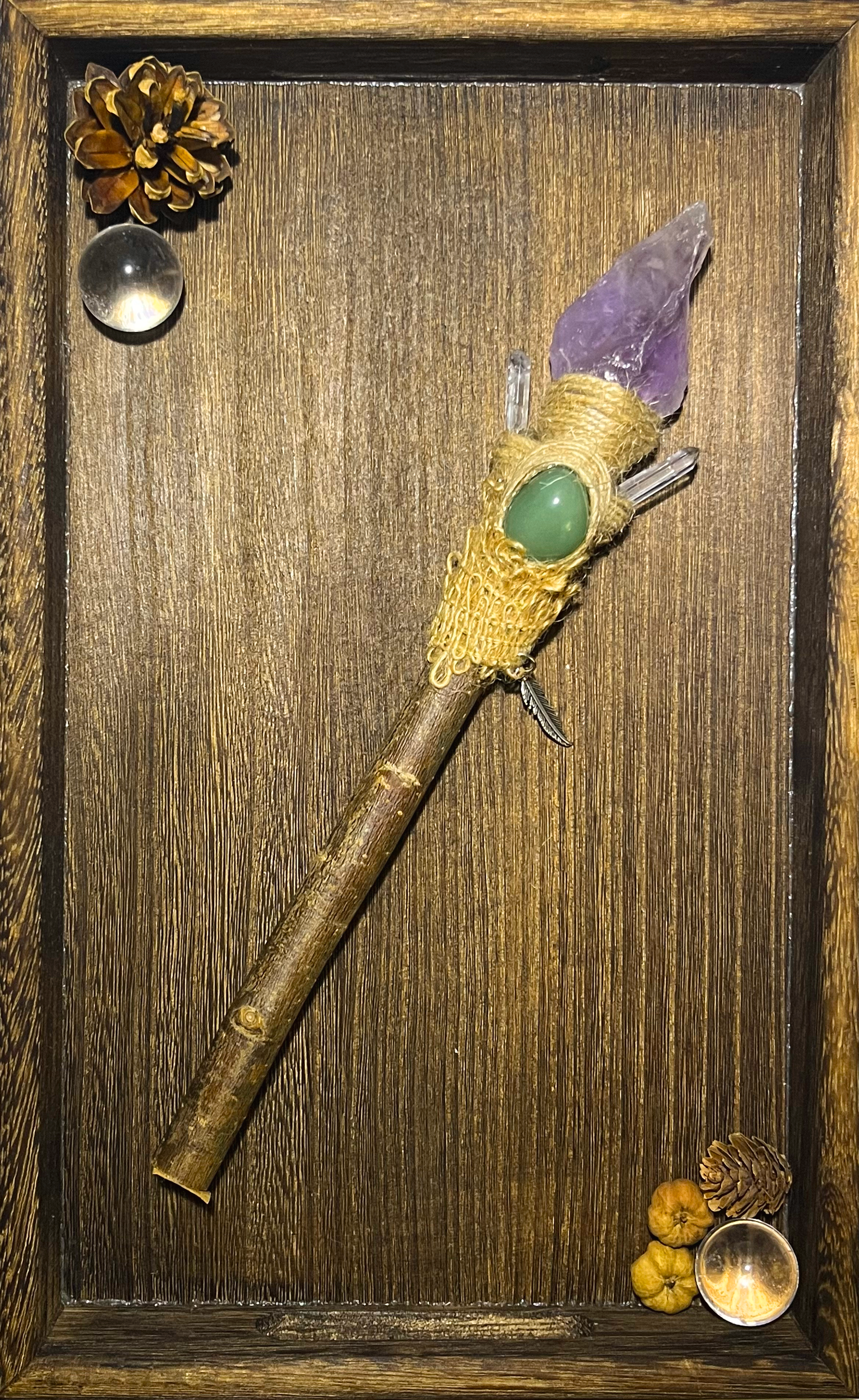 Flat lay of heart healing ritual wand with earthy tones and silver feather charm