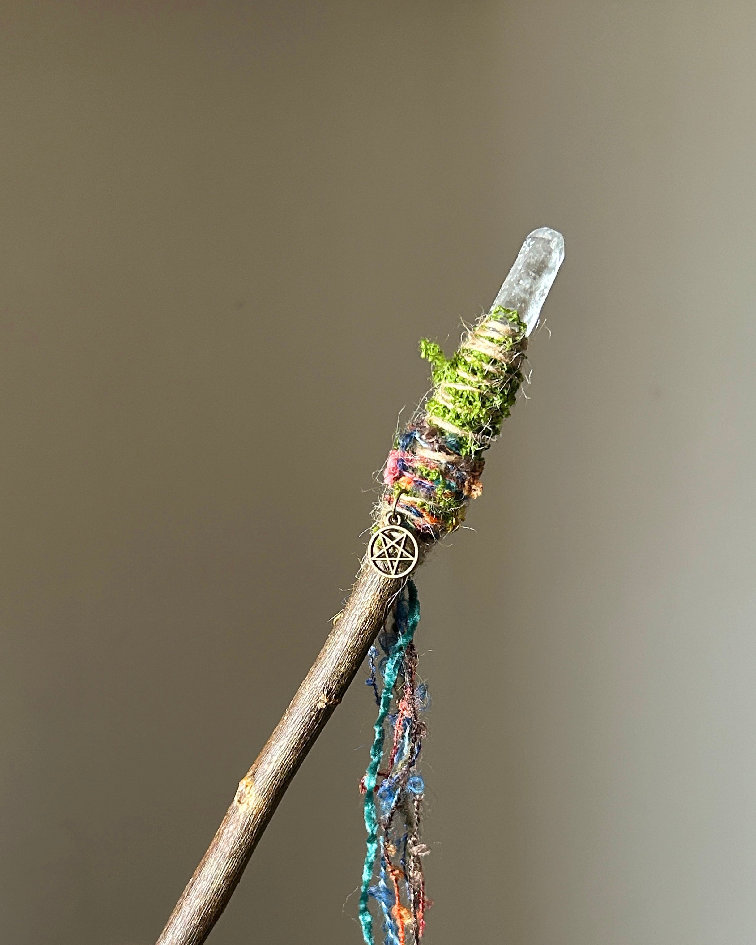 Front view of willow wand with clear quartz tip, moss, and colorful fiber wrapping