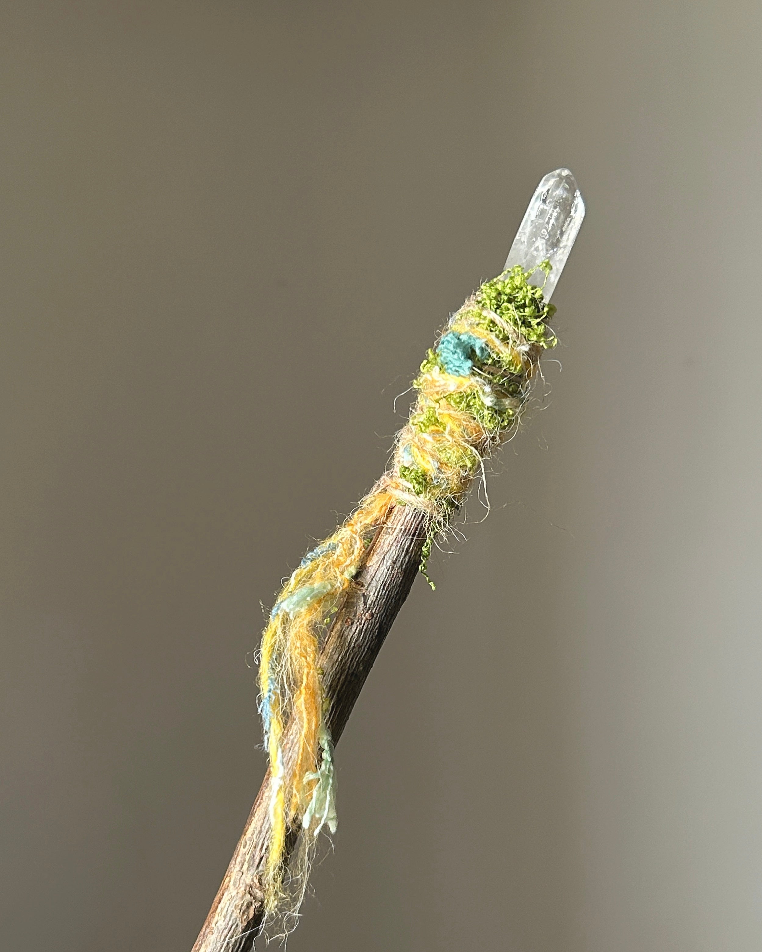 Back view of willow ritual wand with moss and multicolored fibers