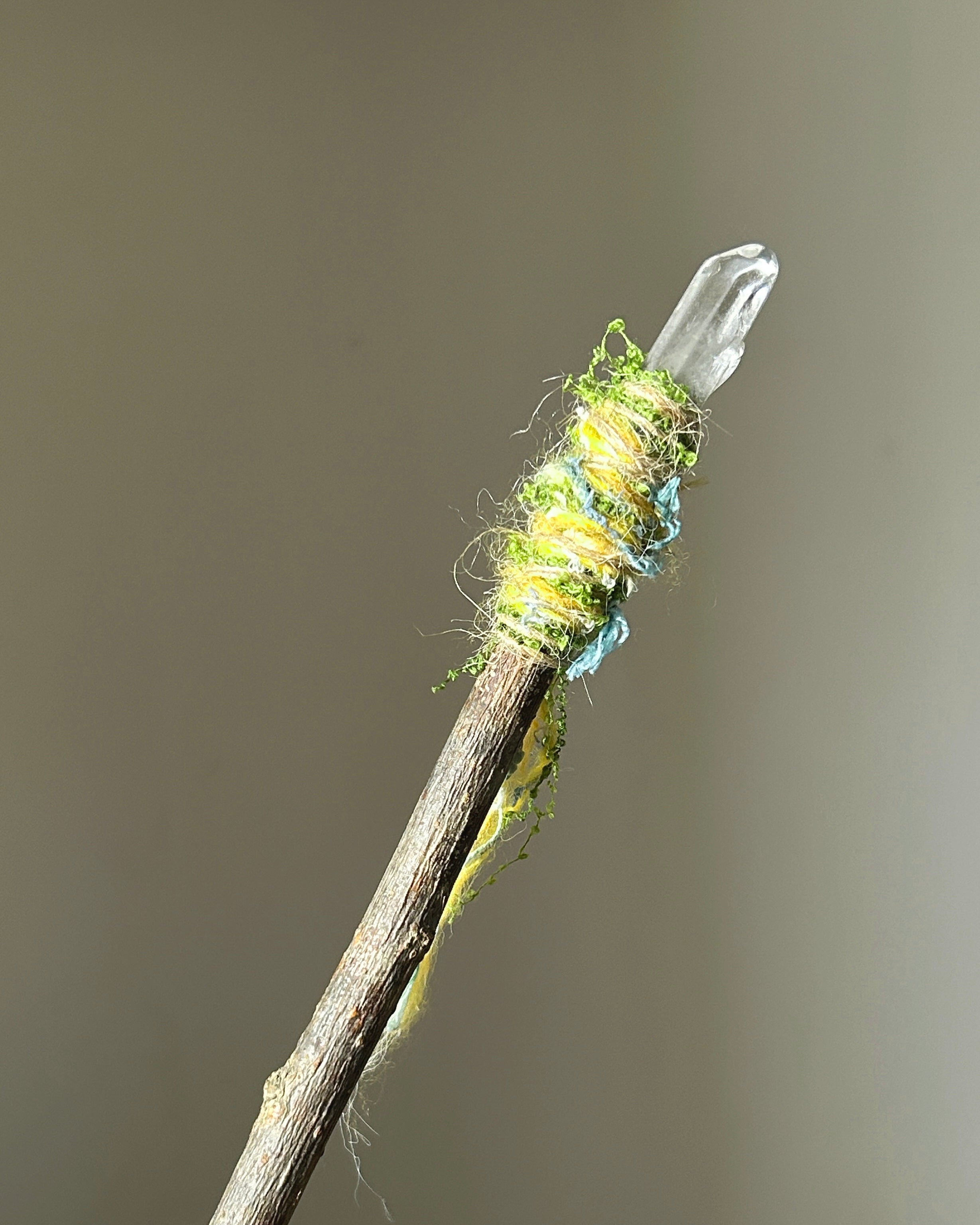 Front view of a willow wand with clear quartz tip and blue-yellow fiber wrapping