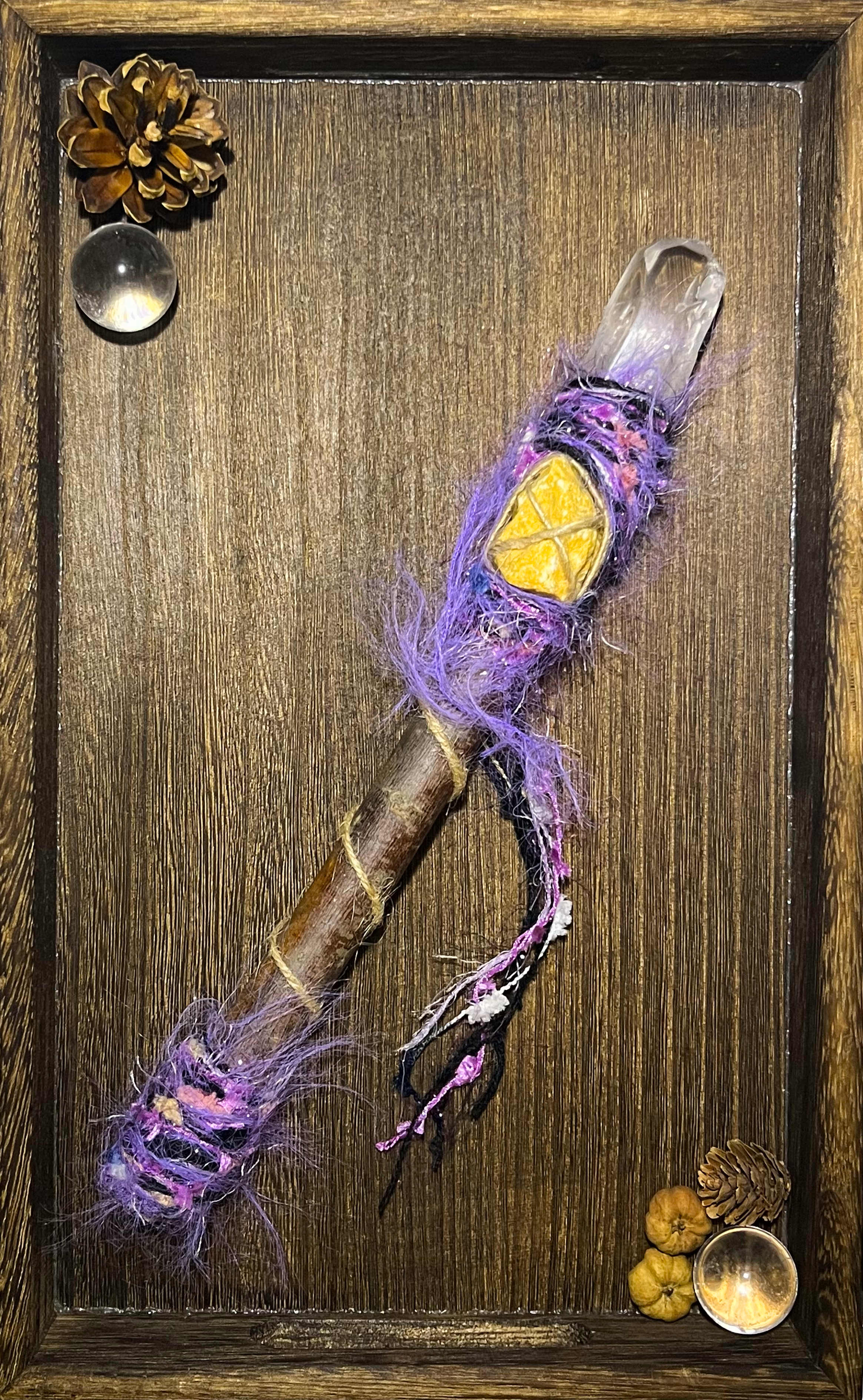 Flat lay of ritual wand with quartz point and solar-colored wrapping on neutral altar dish