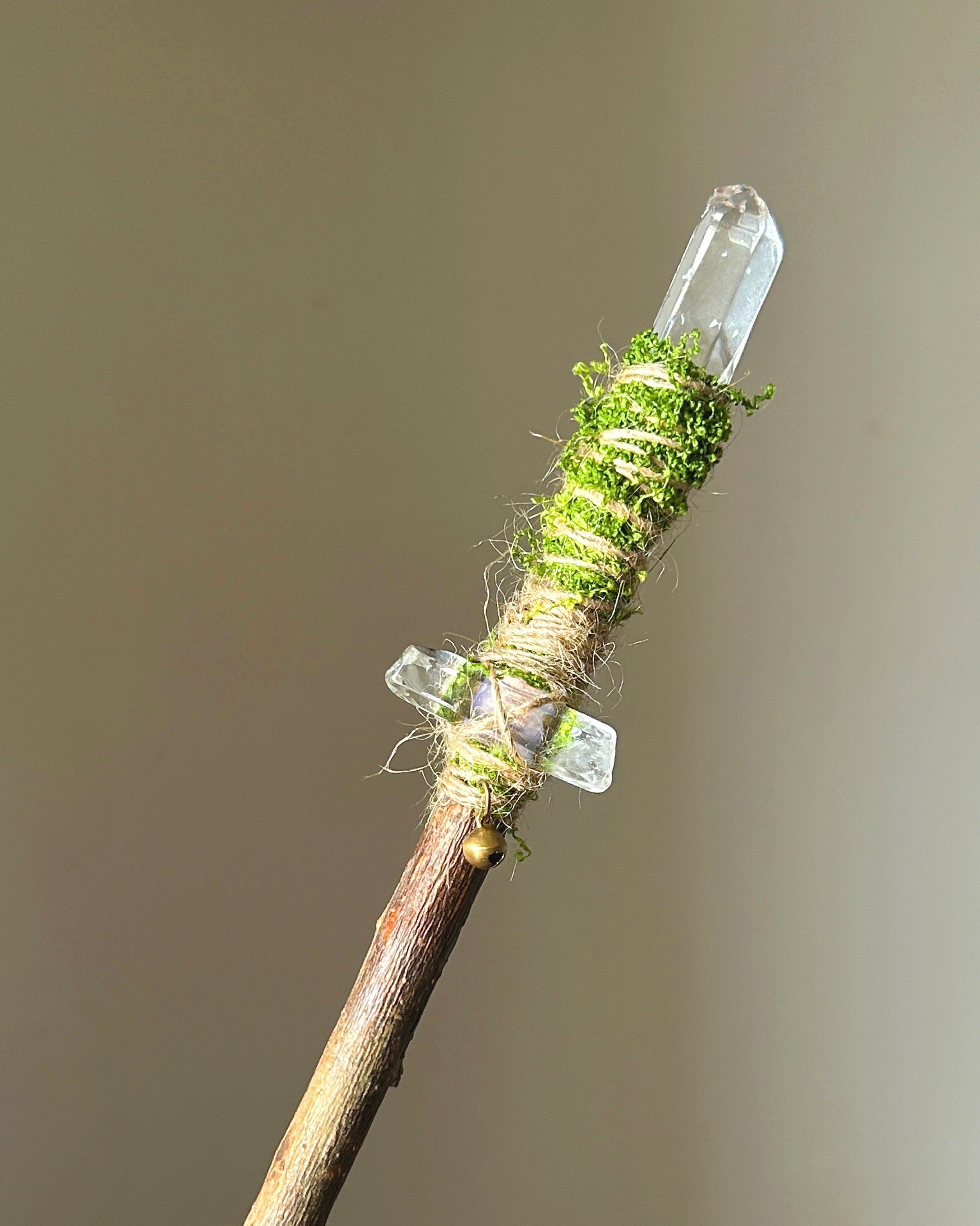 Front view of a handcrafted willow wand with twin clear quartz points and moss wrapping