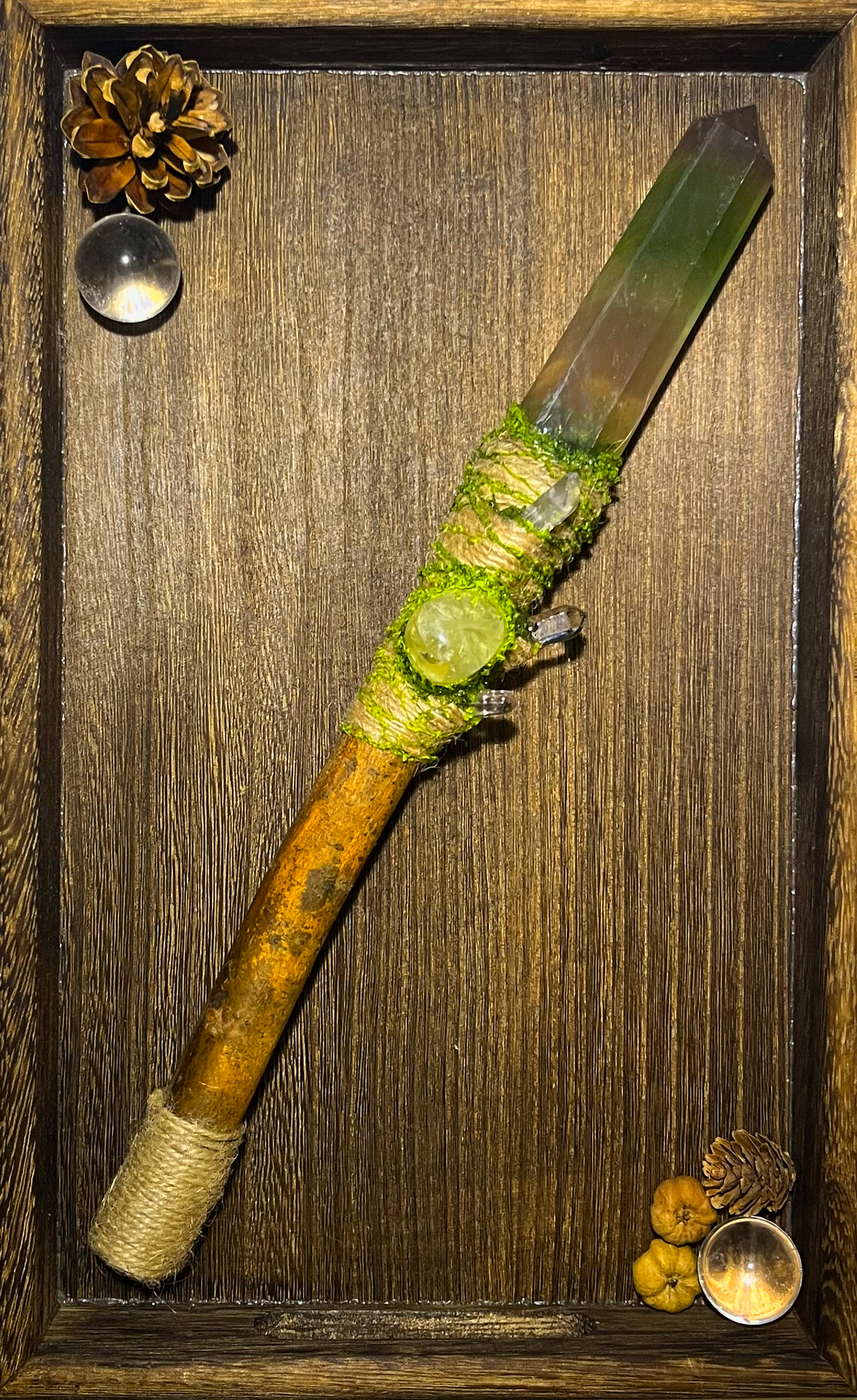 Flat lay of forest-themed ritual wand with soft green tones and woodland textures