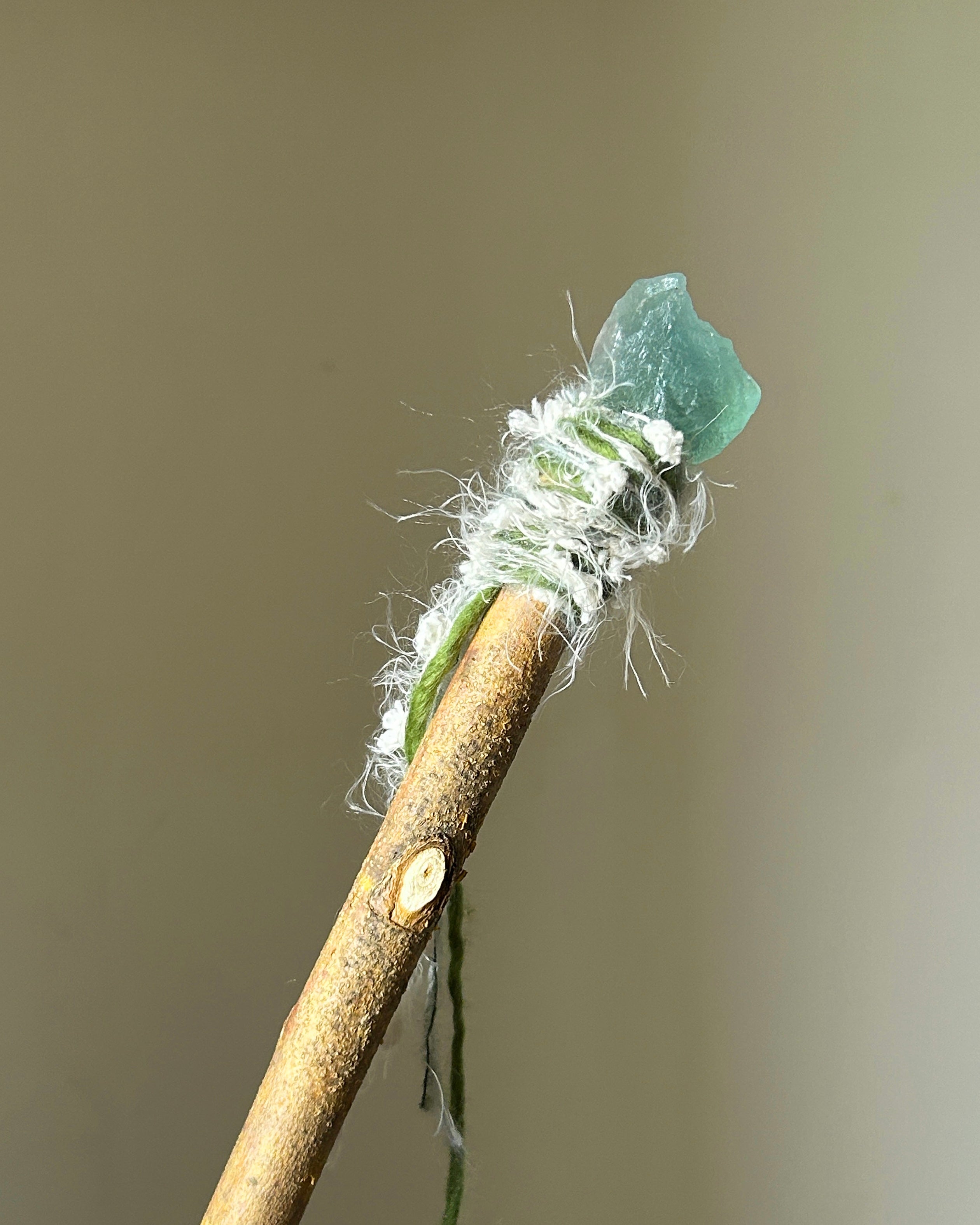 Back view of green fluorite wand with flowing fiber details and natural willow wood