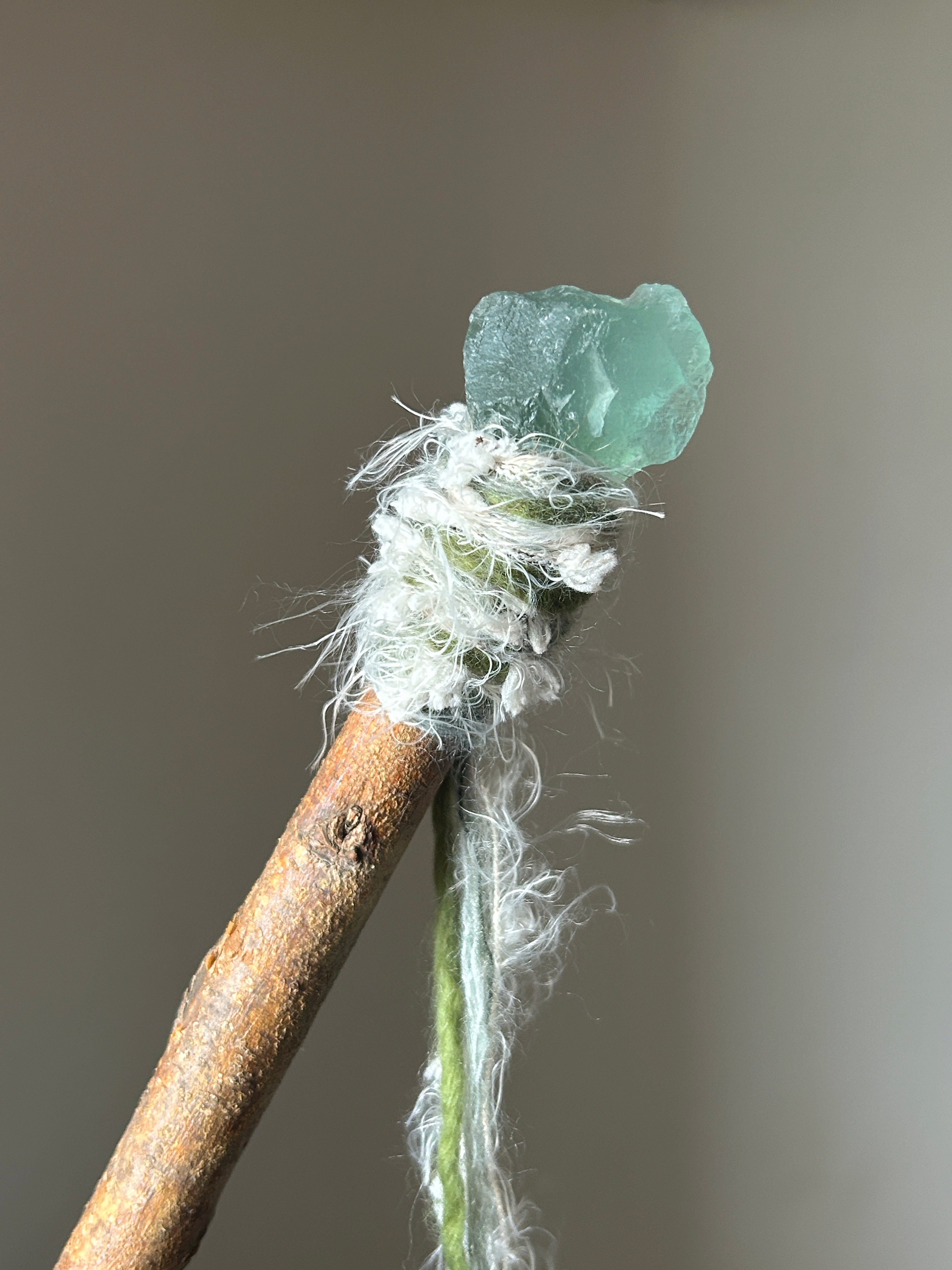 Close-up of raw green fluorite crystal and soft fiber wrapping on ritual wand