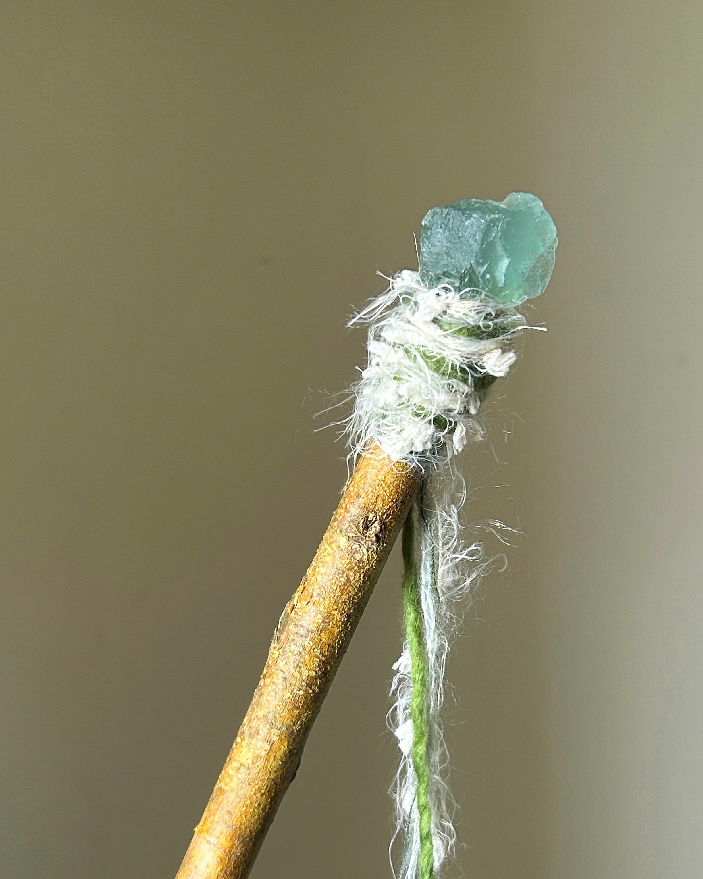 Front view of willow wand with raw green fluorite and soft white-green yarn wrapping