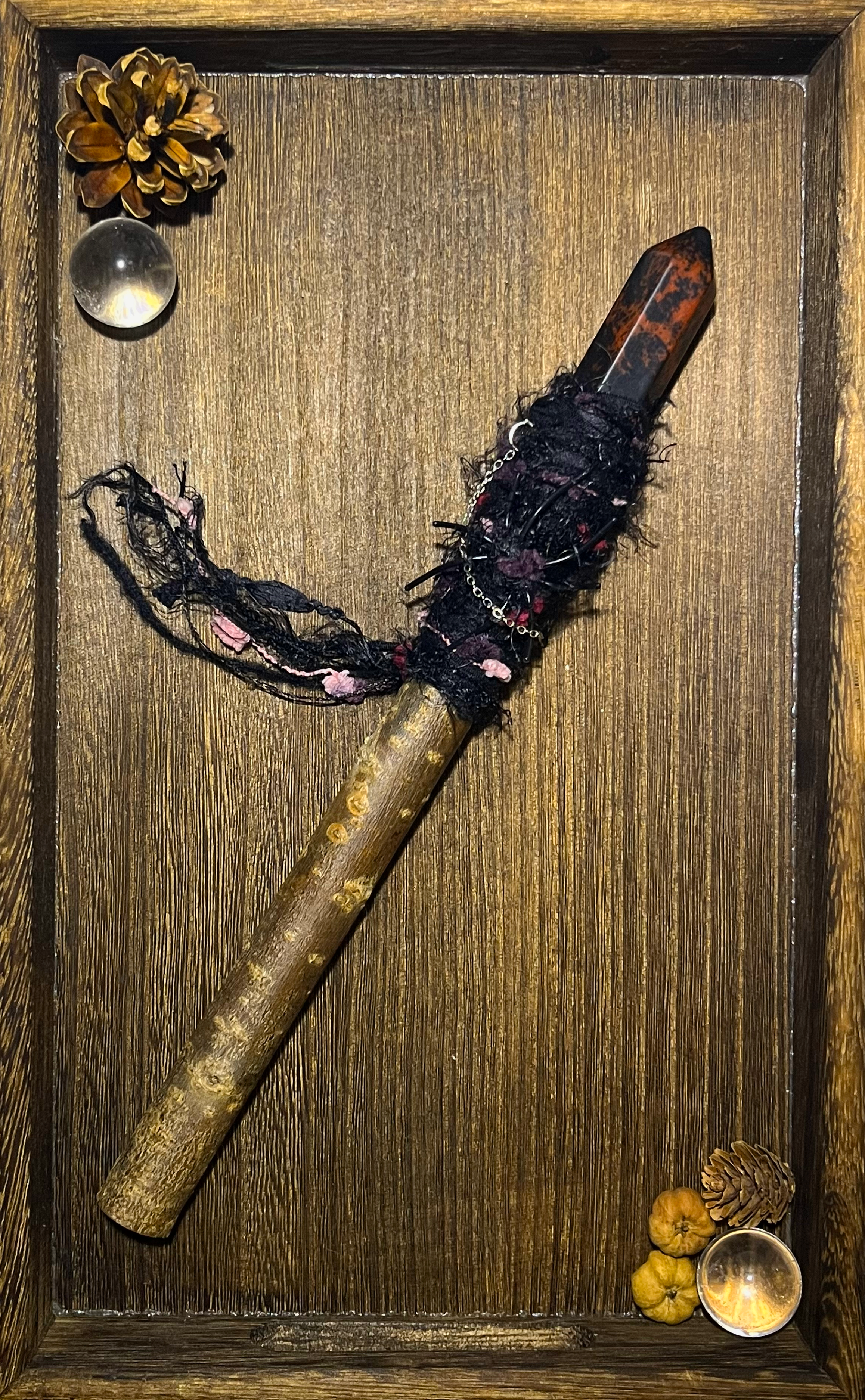 Flatlay showing black-and-red bound protective wand with obsidian tip