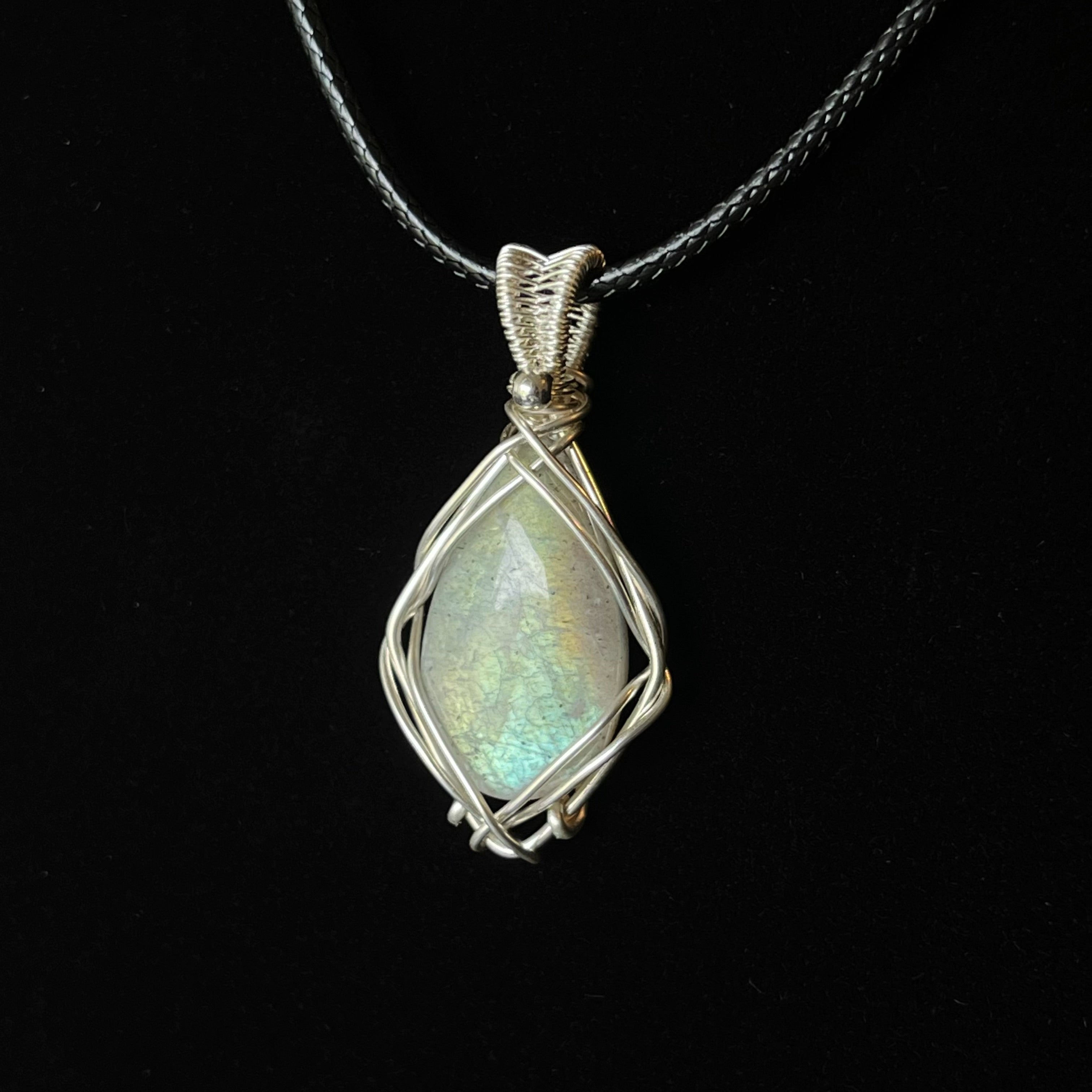 Pale green-blue labradorite pendant wrapped in open silver wire with woven bail