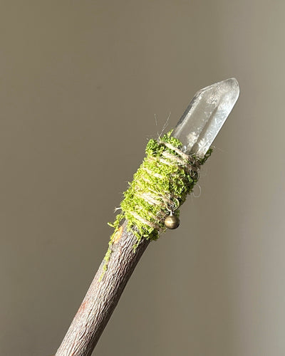 Front view of a handcrafted [wood] wand with [crystal] tip, wrapped in moss and twine