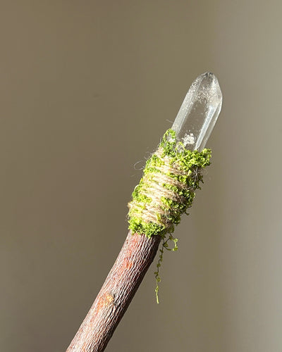Back view of a [wood] wand showing natural grain, moss wrapping, and crystal tip