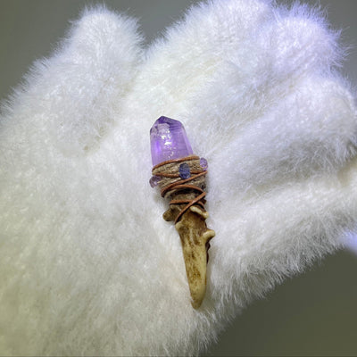 Close-up of high-clarity Cruzite antler wand with enhydro inclusion and amethyst accents, held in a white gloved hand