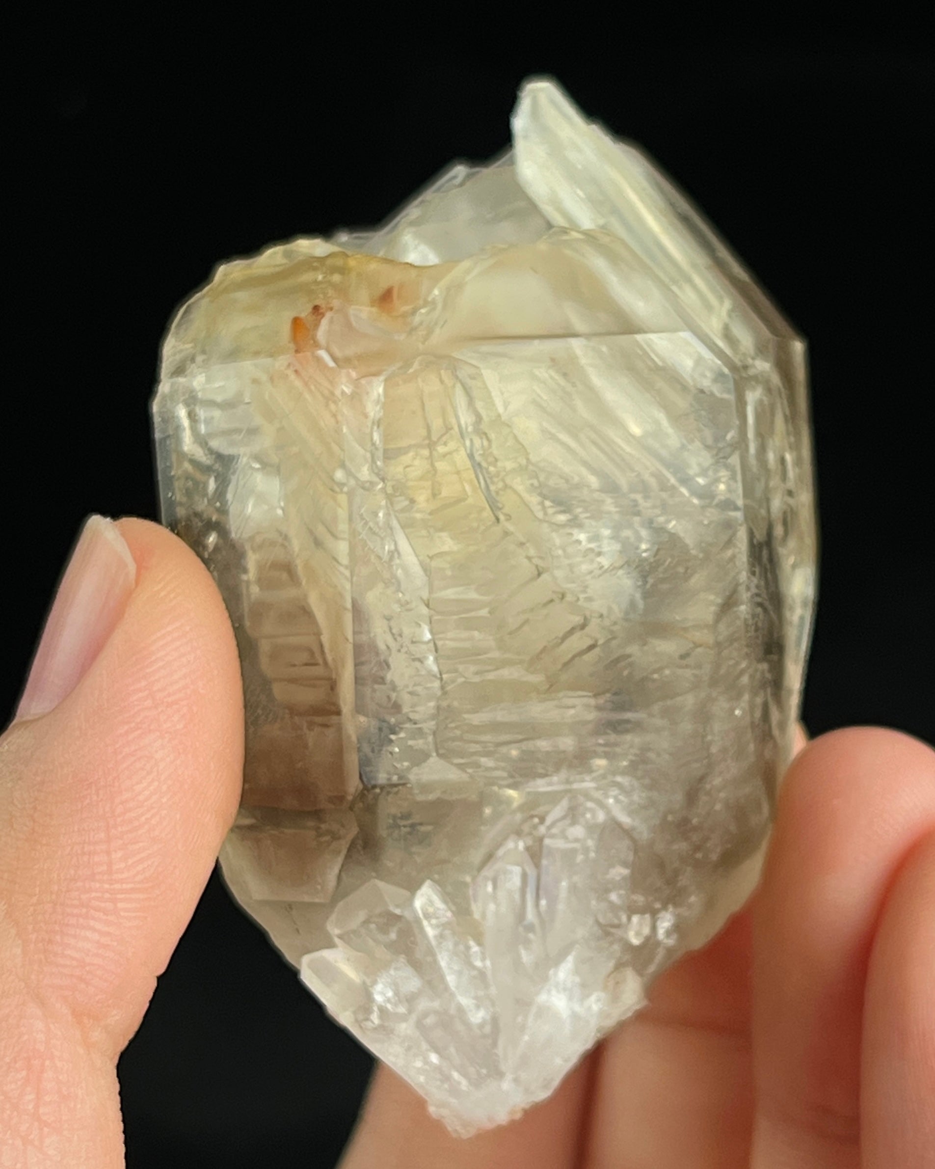 Pale smoky elestial quartz with layered white and reddish clay and companion crystals at the base.