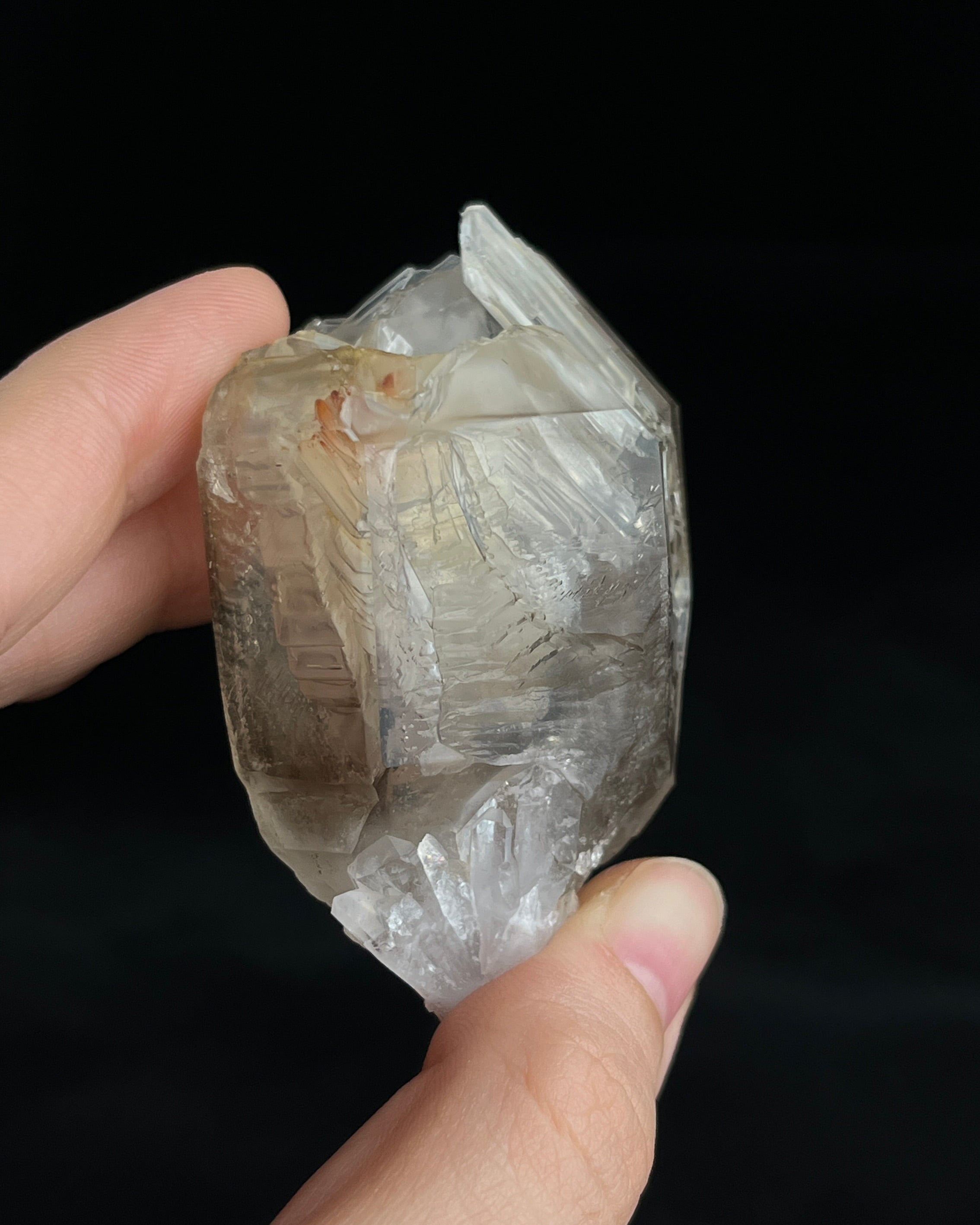 Pale smoky elestial quartz with layered white and reddish clay and companion crystals at the base.1