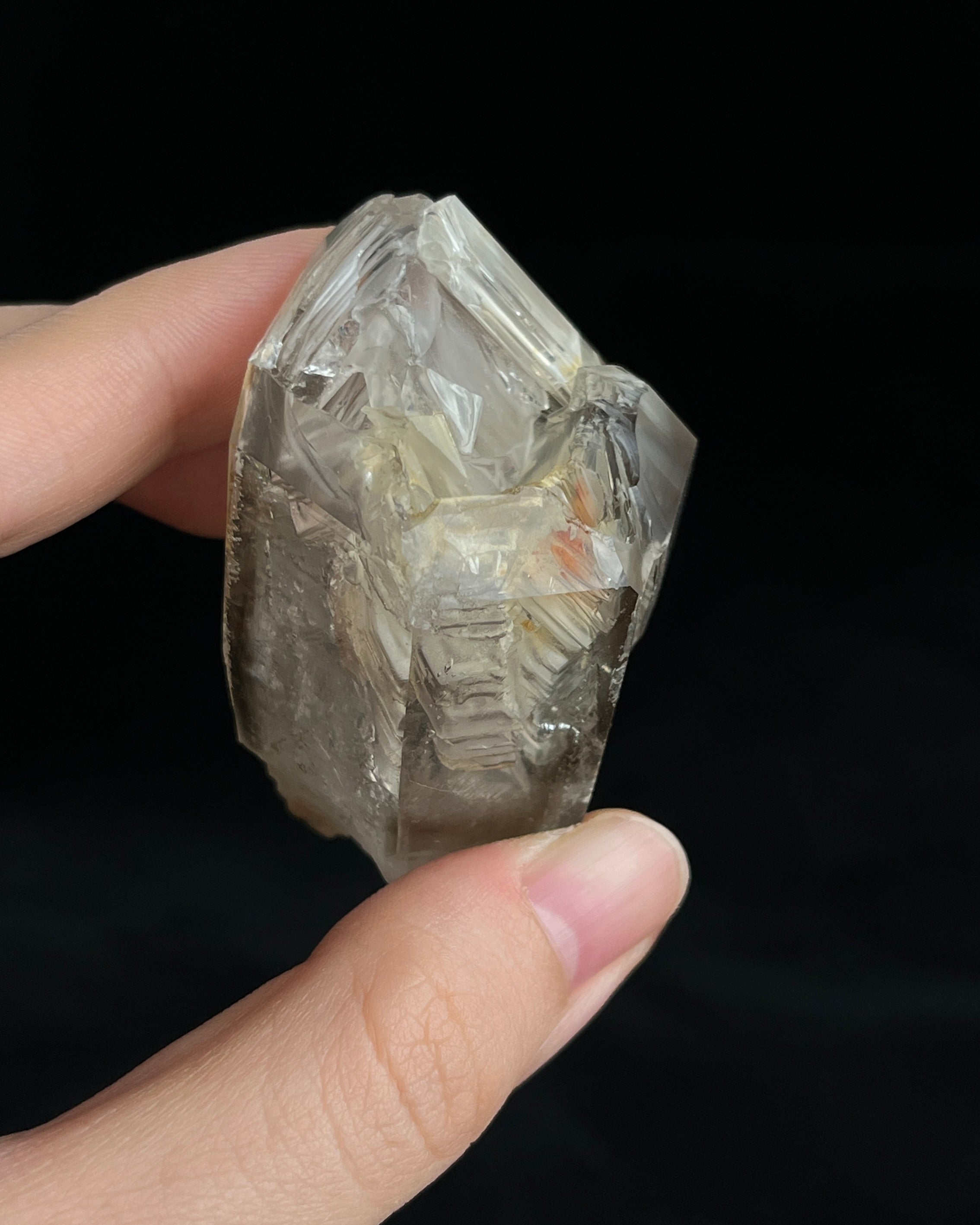 Pale smoky elestial quartz with layered white and reddish clay and companion crystals at the base.6