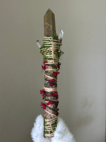 Back view of birch wand with twine, crimson wool, and forest texture