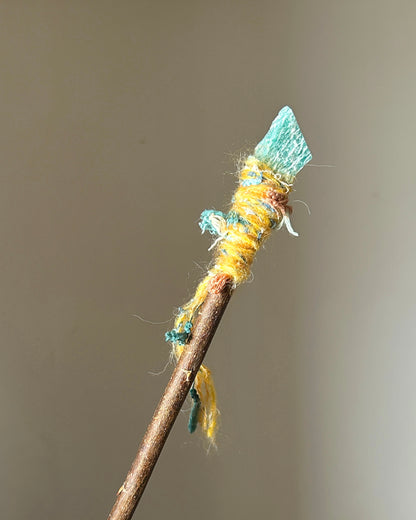 Front view of willow wand with raw amazonite and yellow-turquoise thread wrapping