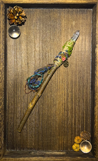 Flat lay of handcrafted elemental wand with quartz point and symbolic wrapping