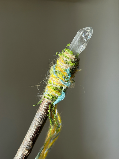 Close-up of clear quartz point with moss and textured blue-yellow wrapping