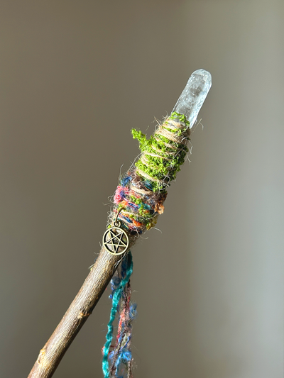 Close-up of quartz point and multicolored fibers with moss and pentacle charm