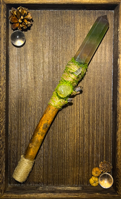 Flat lay of forest-themed ritual wand with soft green tones and woodland textures