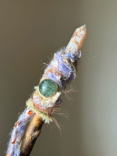 Close-up of pointed Sakura Agate and soft pastel yarn on magical willow wand